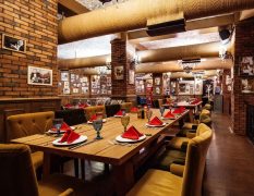 restaurant-hall-with-red-brick-walls-wooden-tables-pipes-ceiling_140725-8504